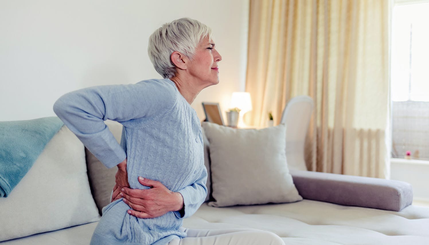 older woman holding her lower back in pain