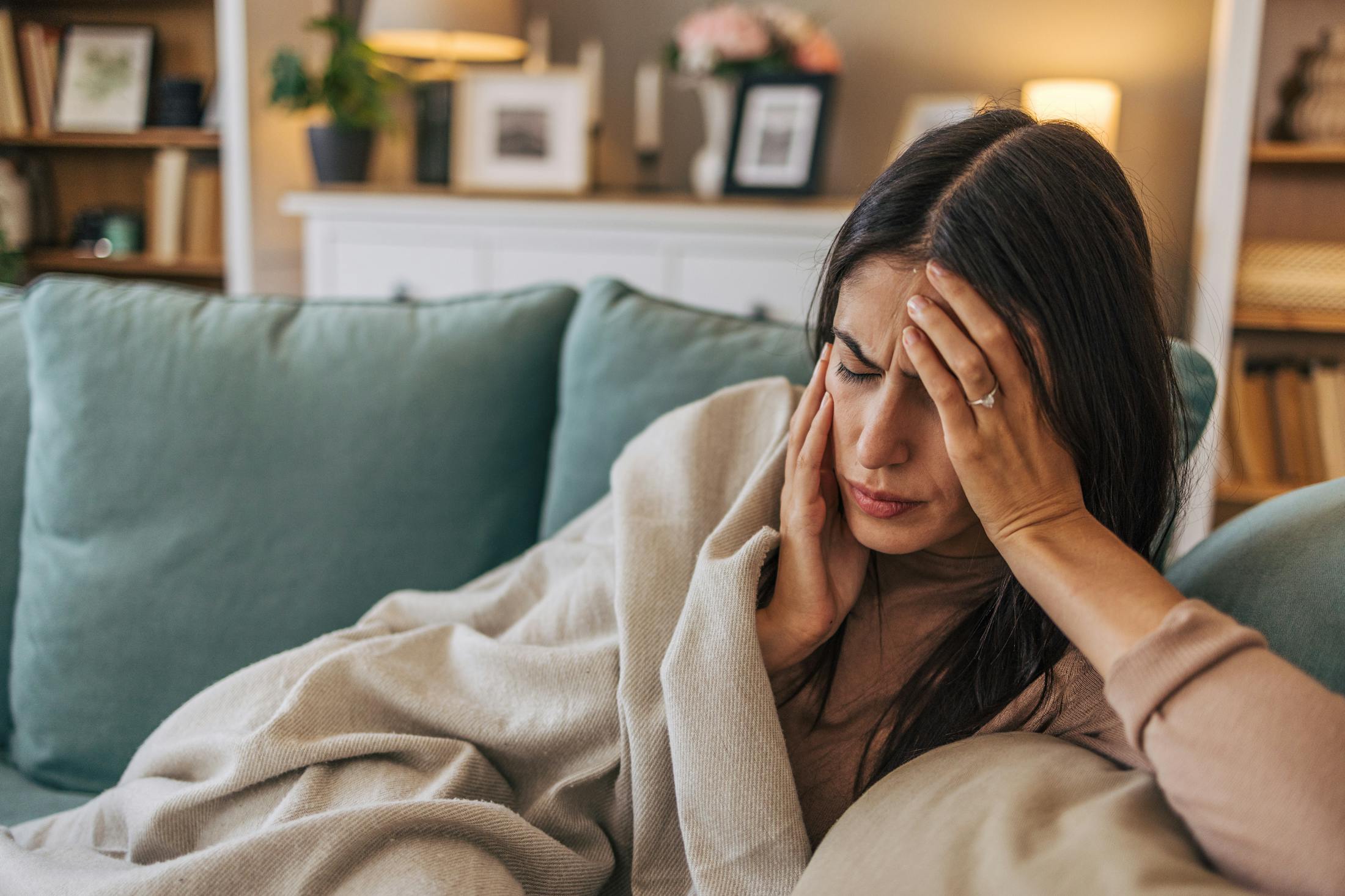 woman laying on couch in pain from a migraine