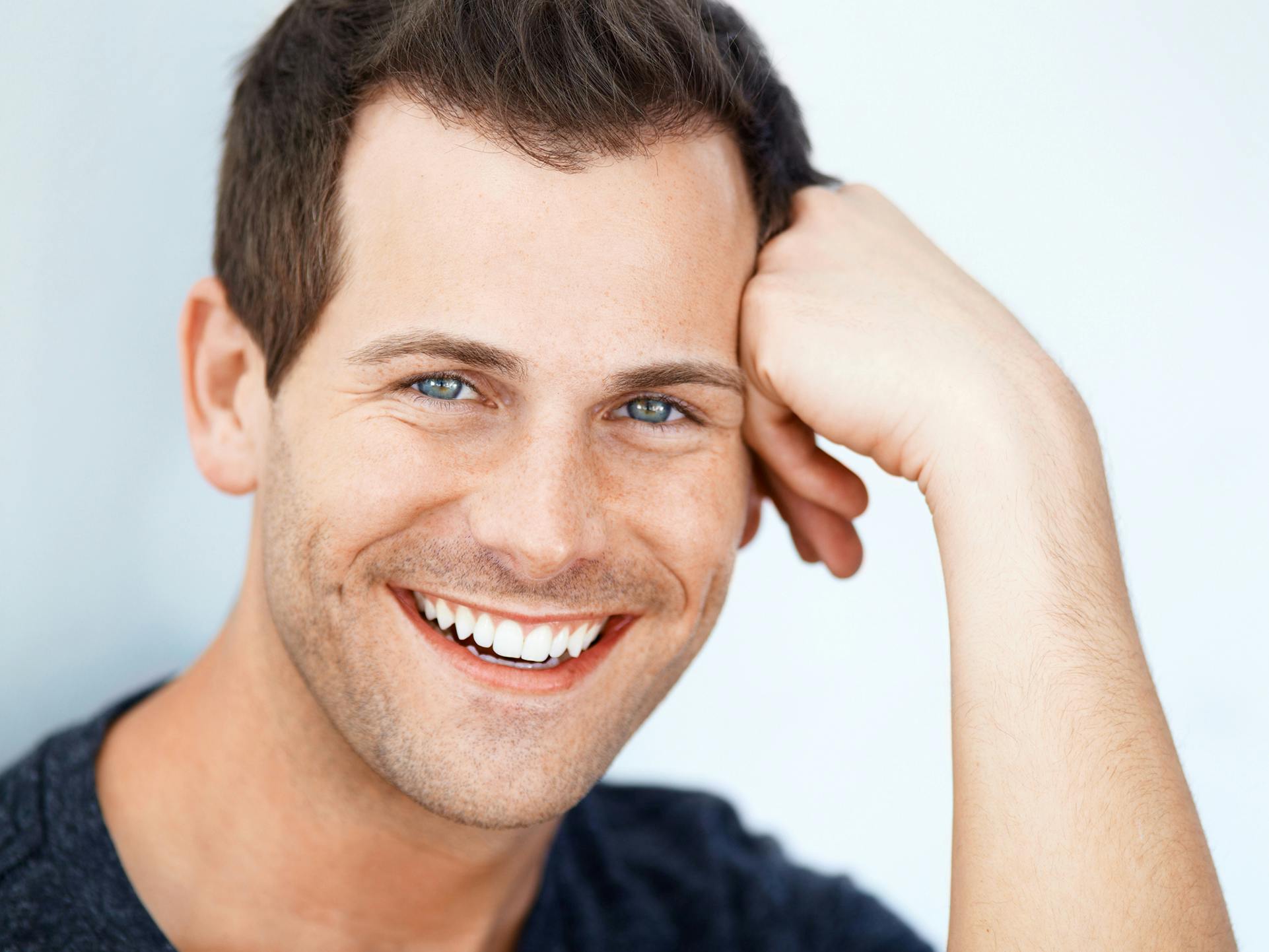 man smiling with head resting on his hand