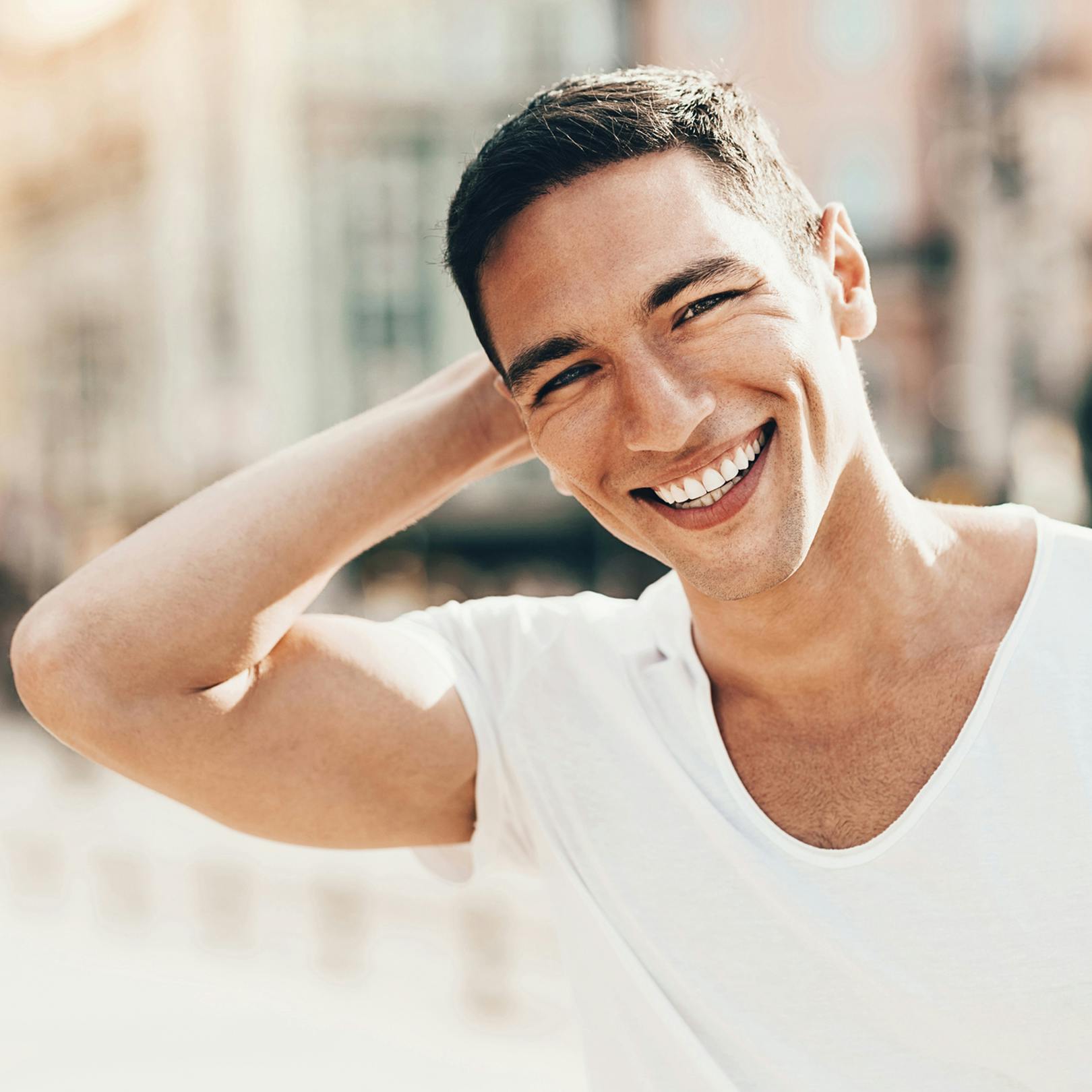man smiling with hand touching back of his head