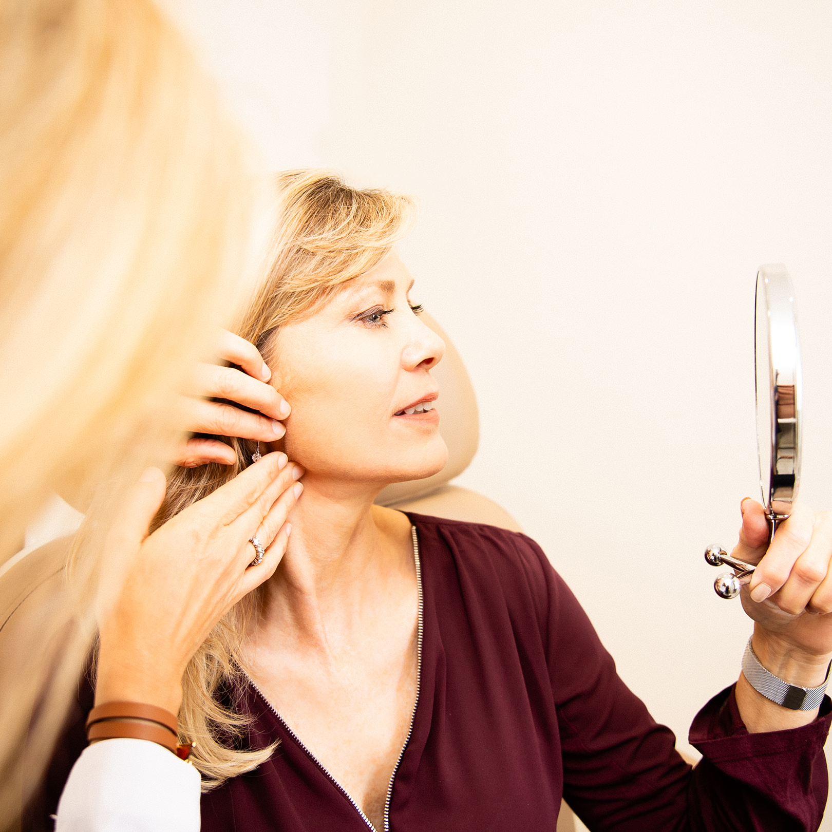 doctor touching client face as she looks in mirror
