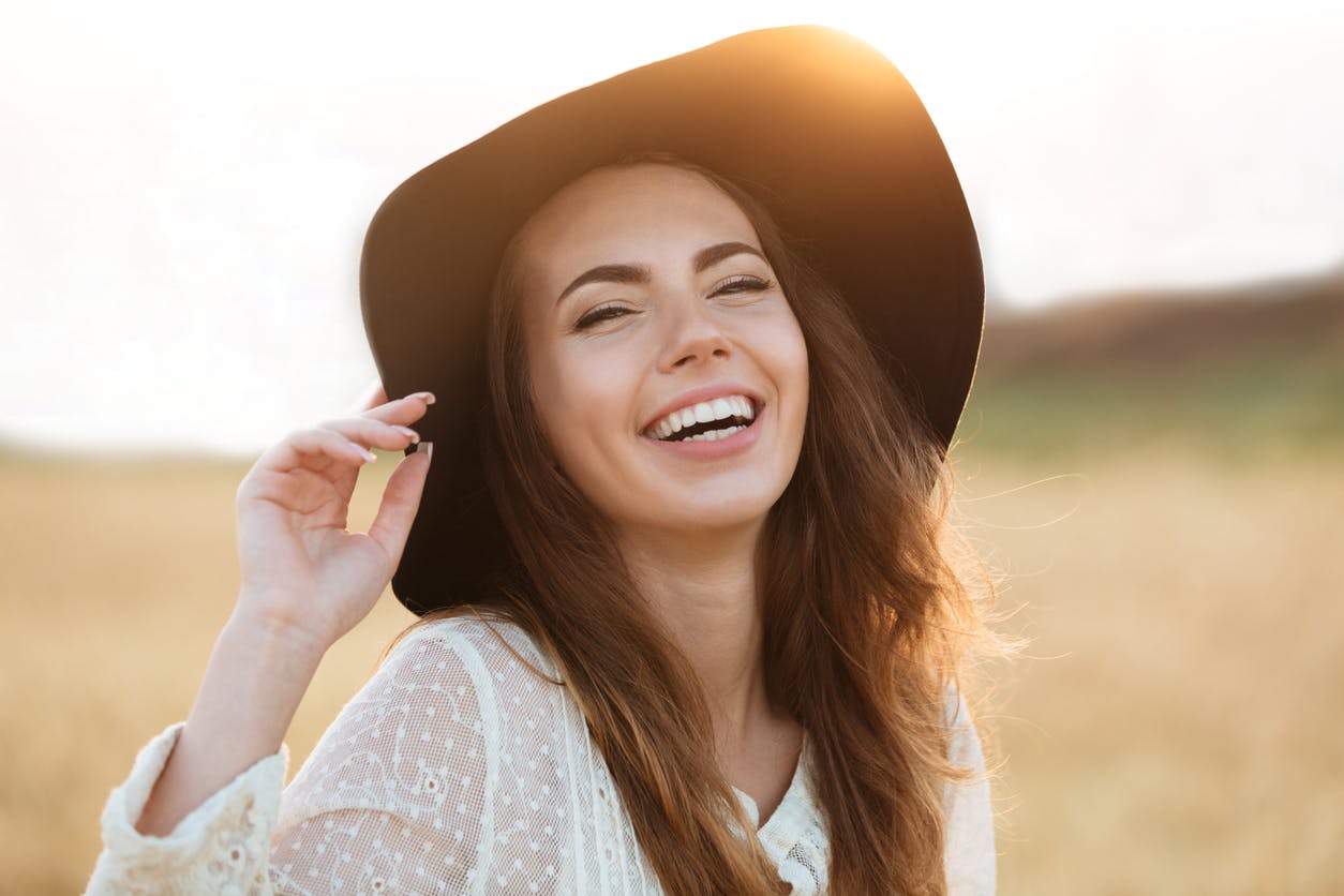 Woman smiling in sun with hat on