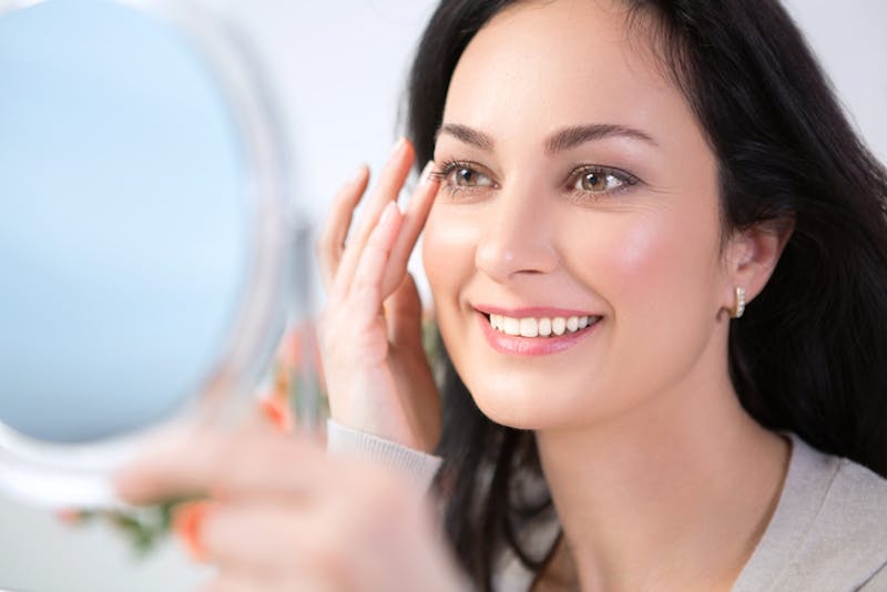 woman smiling at her reflection in the mirror