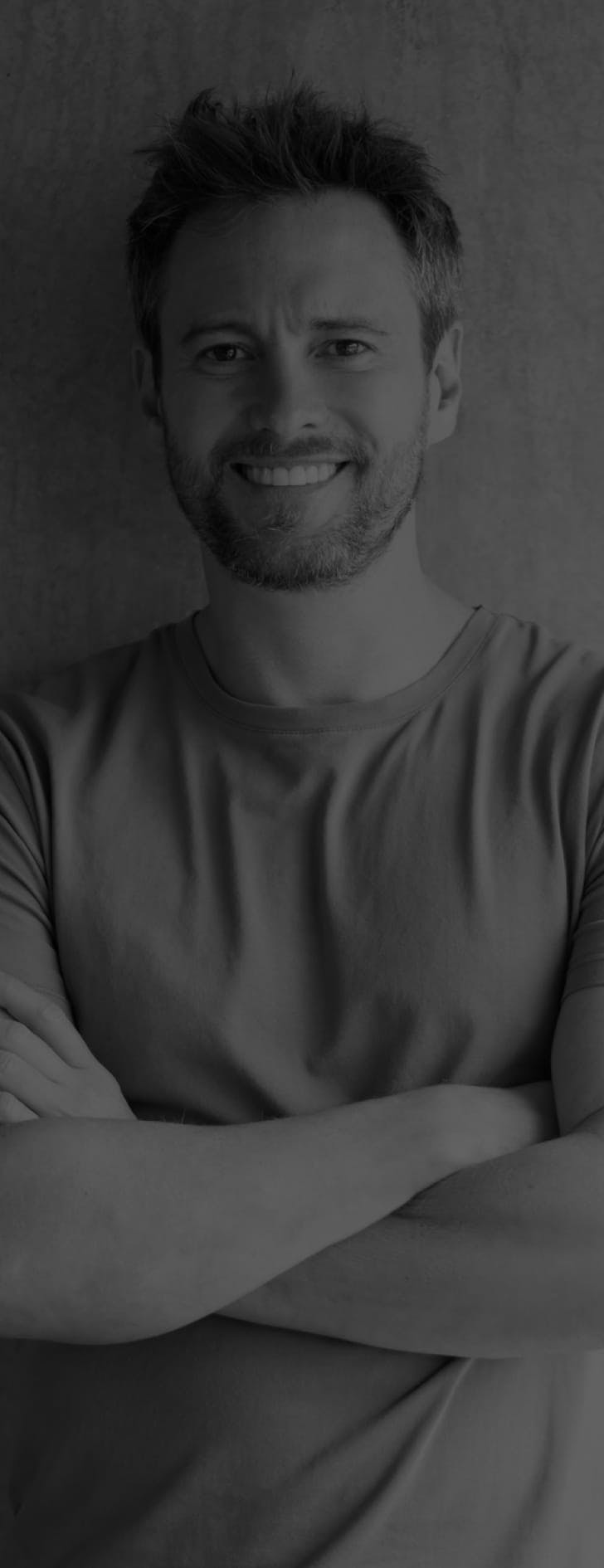 Man smiling and standing with his arms folded