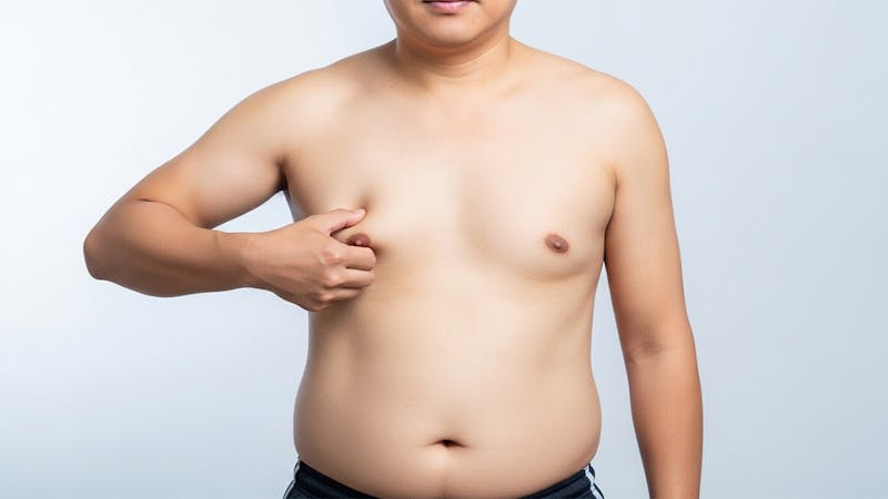 What Causes Gynecomastia in Men - Common Triggers Explained Blog Image - Man without shirt pinching his nipple