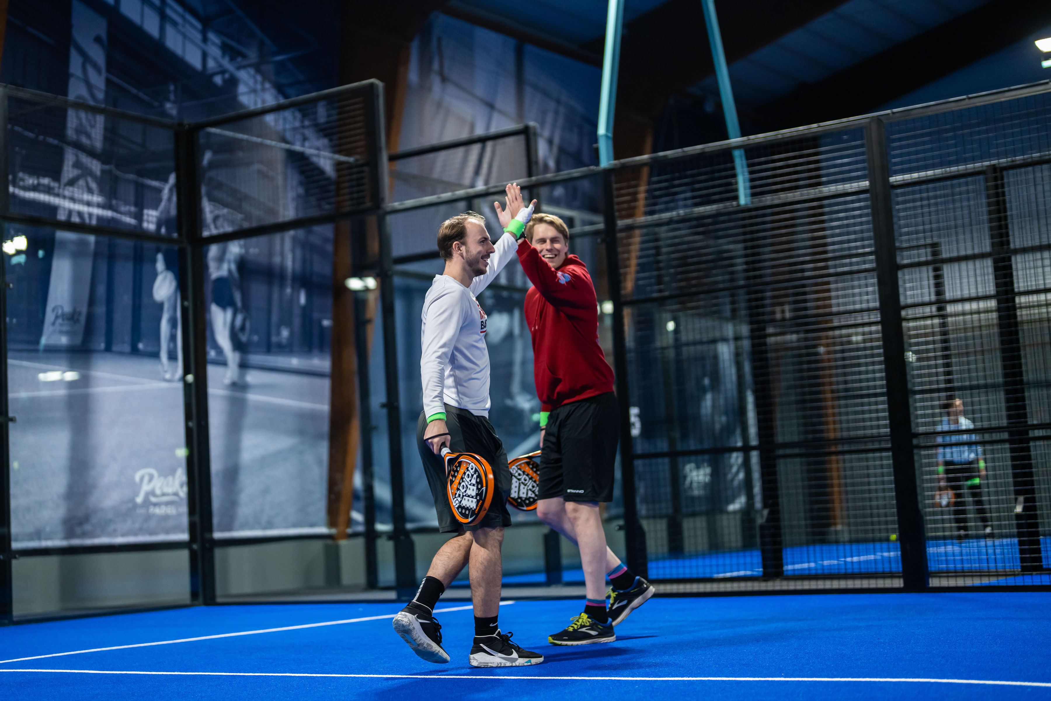 Partners van Peakz doen een high five op de padelbaan
