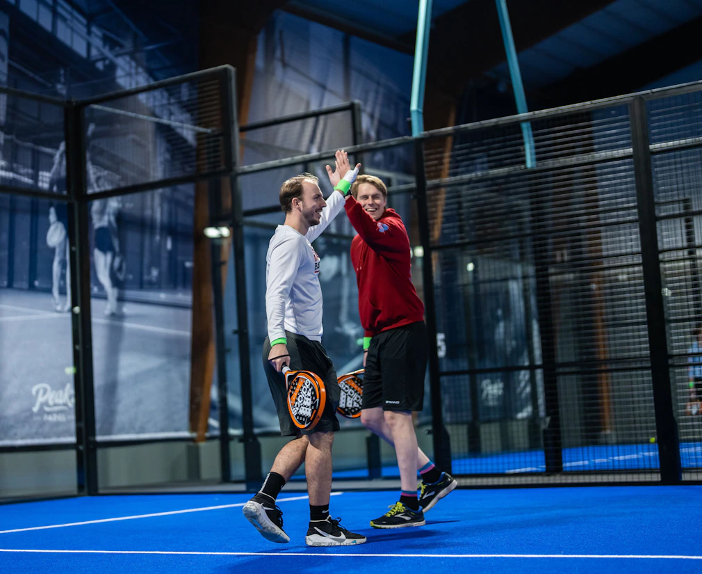 Partners van Peakz doen een high five op de padelbaan Partners van Peakz doen een high five op de padelbaan