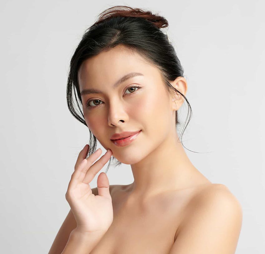 Woman with dark hair touching her face