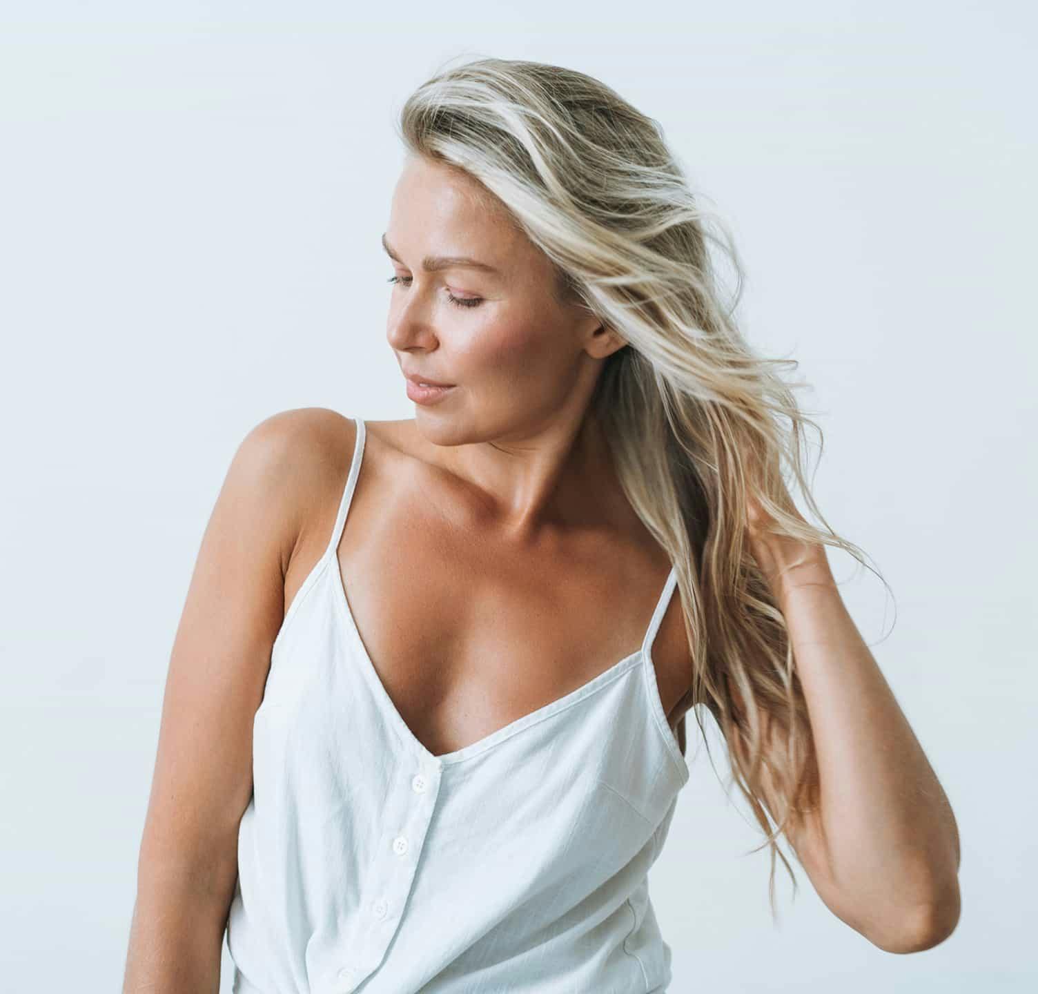 Woman with blonde hair wearing a white tank top