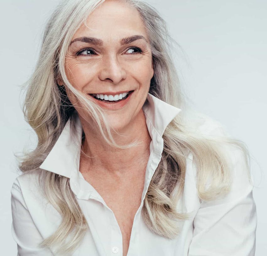Woman with gray hair wearing a white top