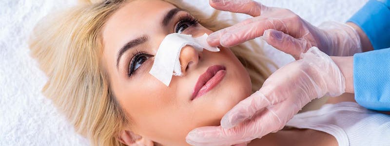 woman with a bandage on her nose after surgery