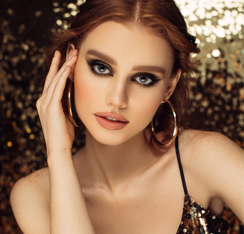 Woman with dark curly hair wearing gold hoops