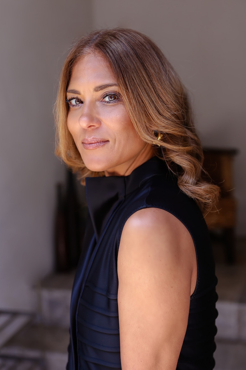 Woman in her 50's having her portrait taken in a sleevless blouse, showing the potential results of a mini facelift in Beverly Hills with Dr. Torkian