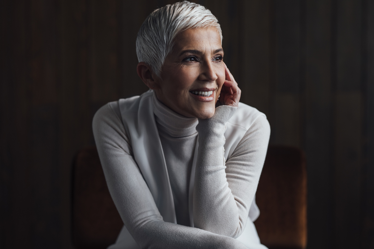 Woman in her 60s smiles looking away from camera to highlight her defined jawline to emulate the potential results of a facelift in Beverly HIlls with Dr. Torkian
