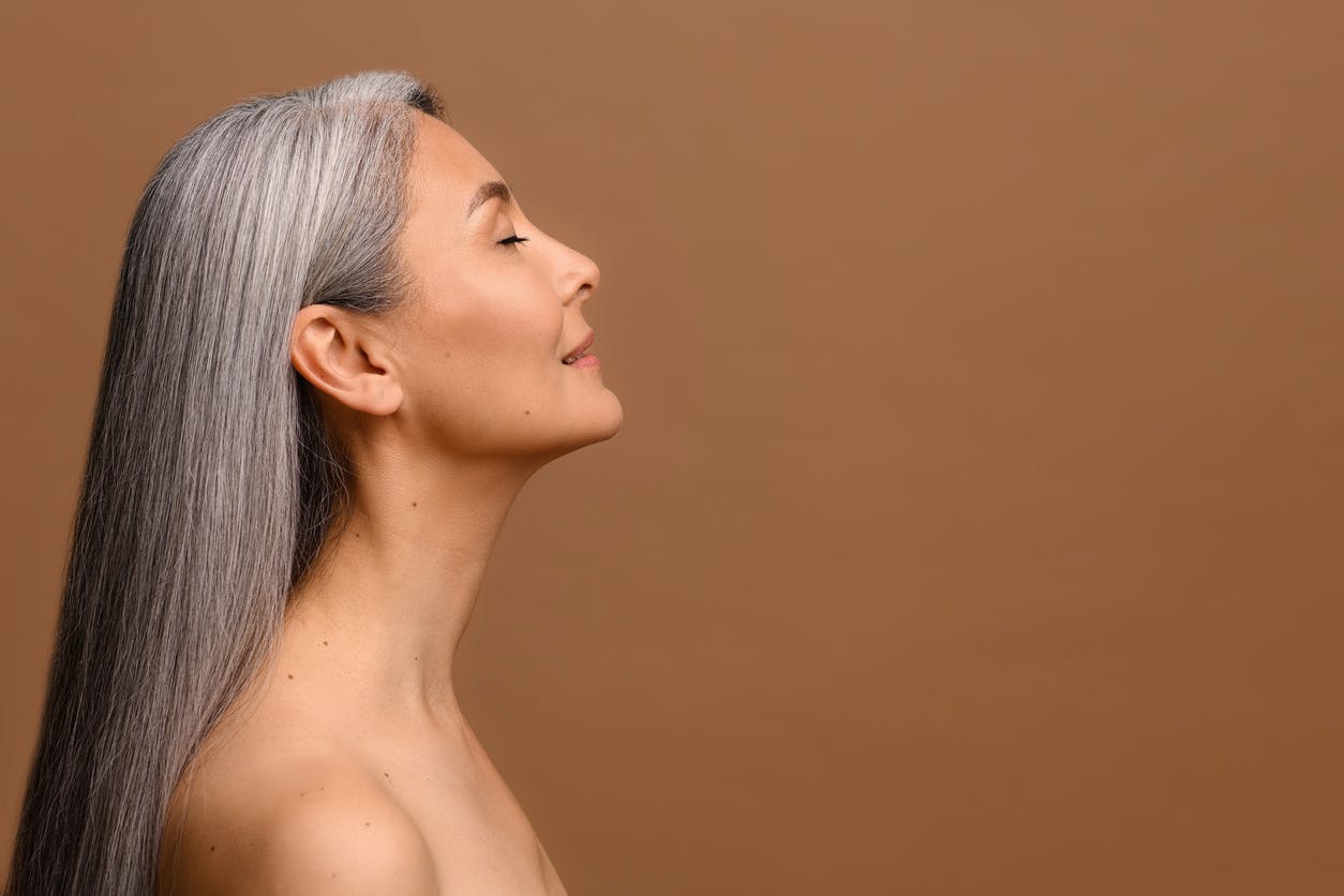 Older woman in her late 50s looks up to show off her neck in a studio shoot. This is to show the possible results of a neck lift in Beverly Hills with Dr. Torkian