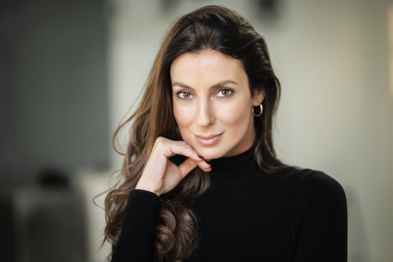 Woman in mid 40s with long hair looks at camera with a small contented grin. Her youthful appearance, shows the potential results of a mini facelift in Beverly Hills with Dr. Torkian