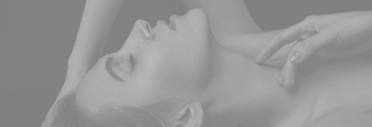 Woman lies down with eyes closed on back with hand by neck in suductive manner