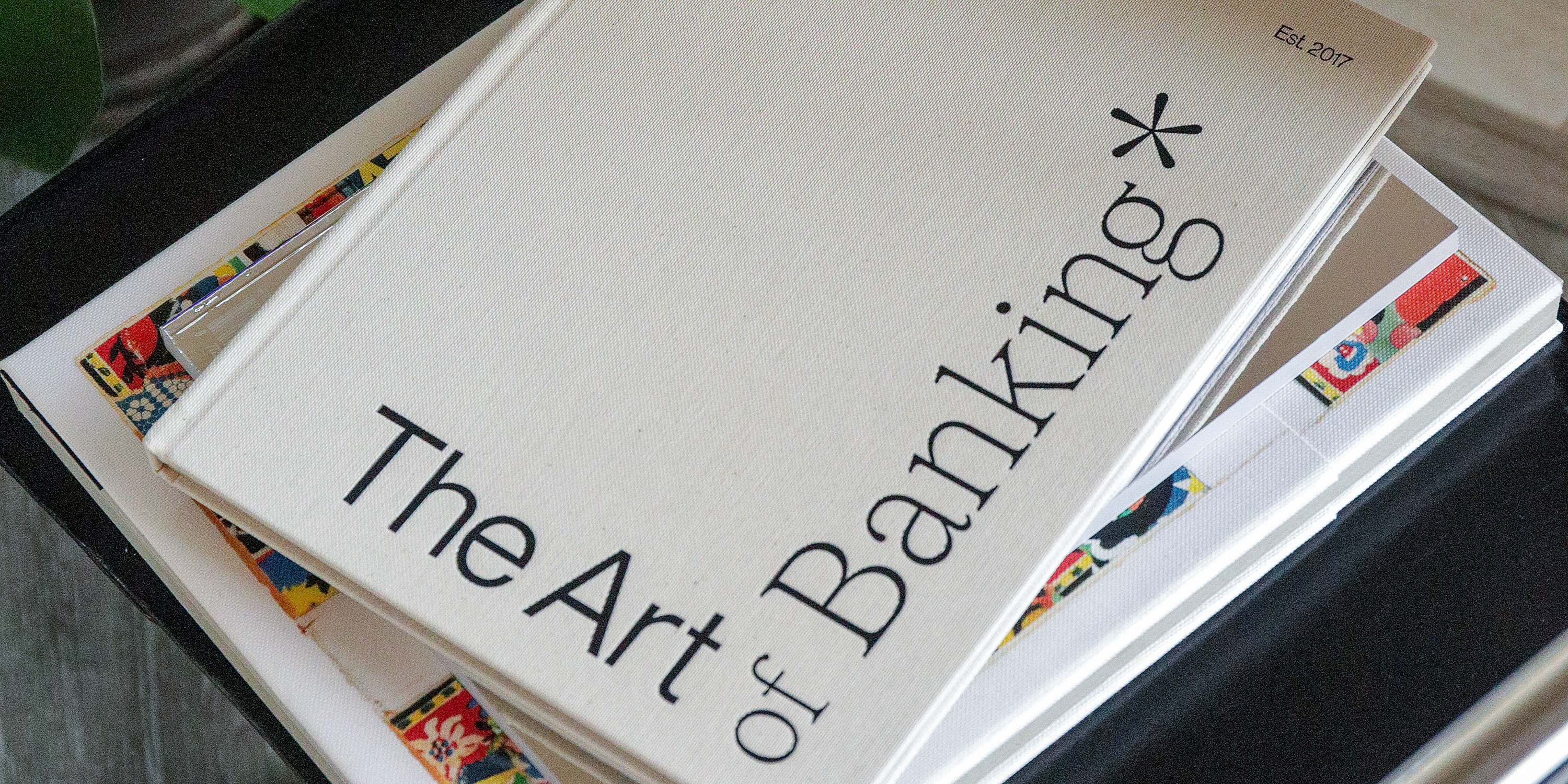 2-1 Culture book 02 Mercury culture book, titled "The Art of Banking," is featured on the top of a stack of books on a black leather chair.