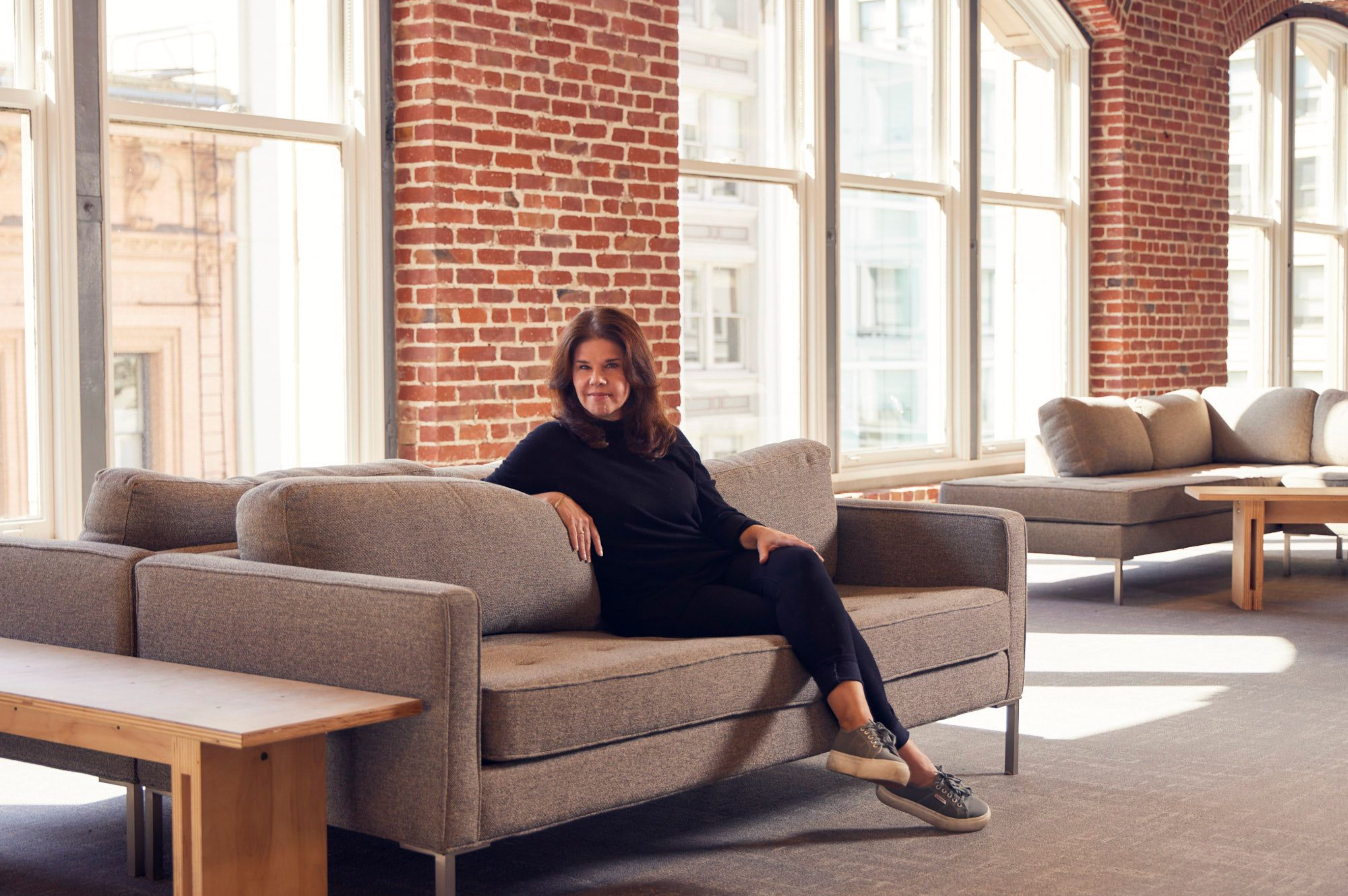 Carolynn Levy lounging on a sofa in a brick building