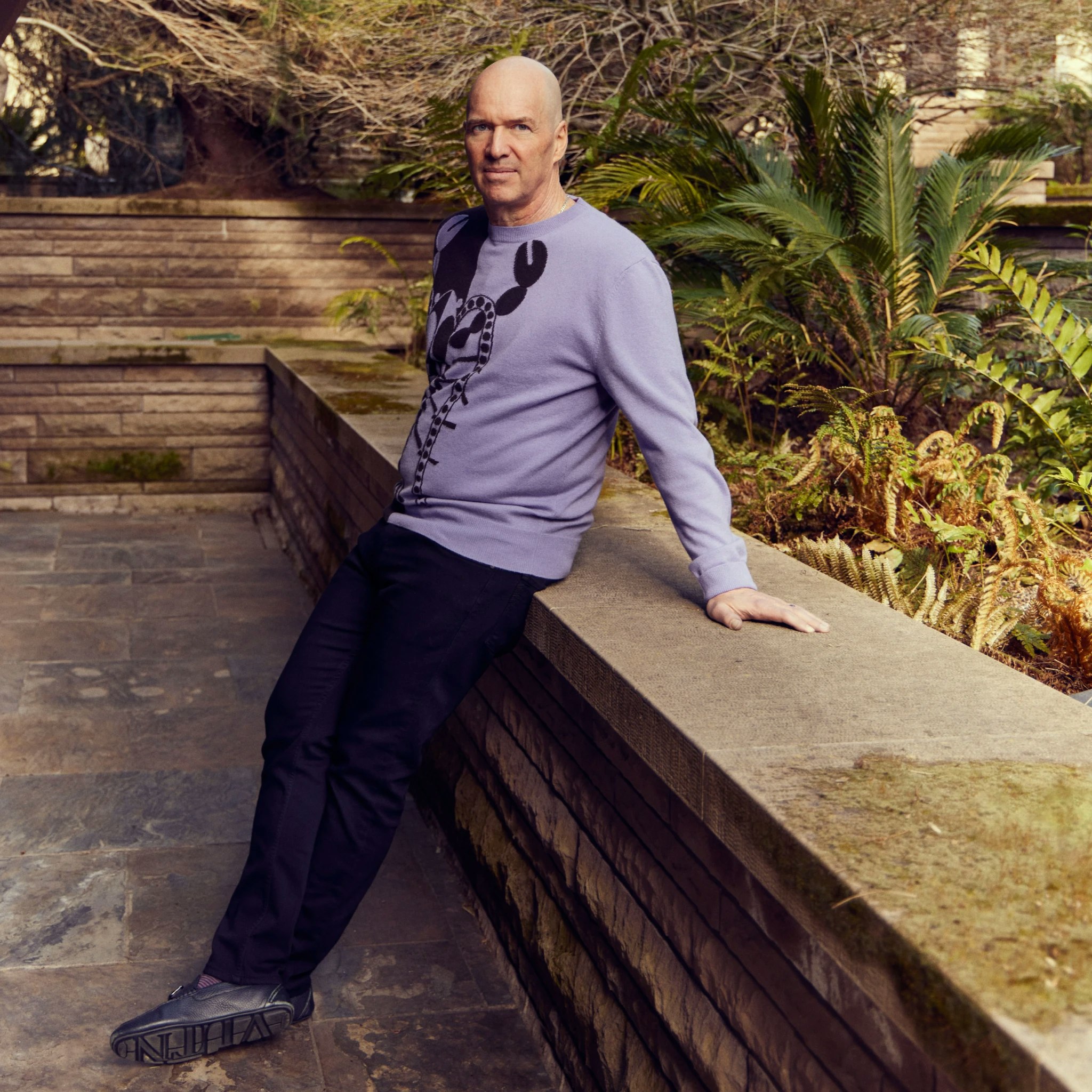 Ben Horowitz leaning on a cement wall in a lush landscaping environment
