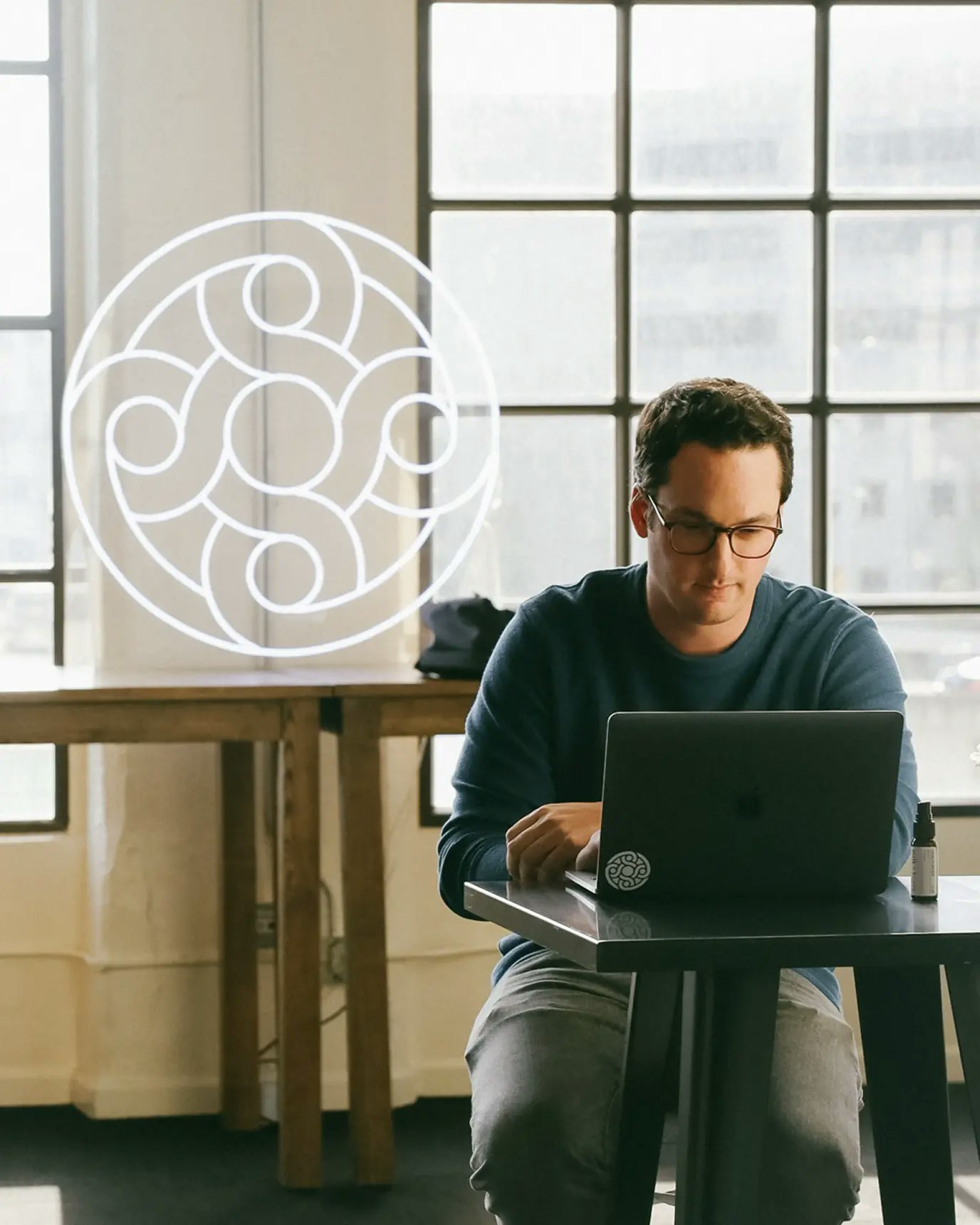 Person on their laptop with Mercury logo neon sign in the background