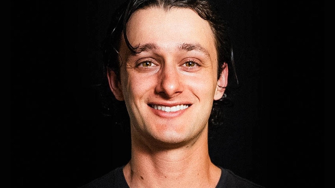 Smiling man wearing black T-shirt looks directly at the camera.