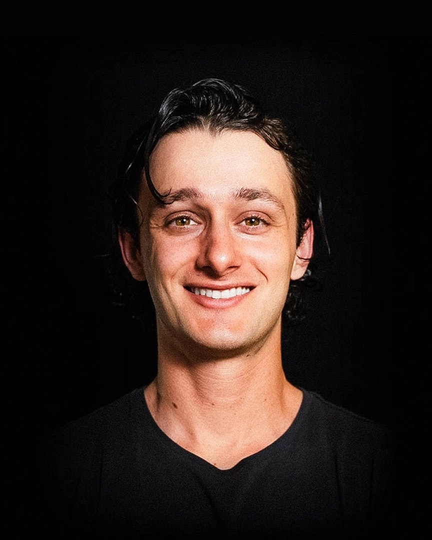 Smiling man wearing black T-shirt looks directly at the camera.