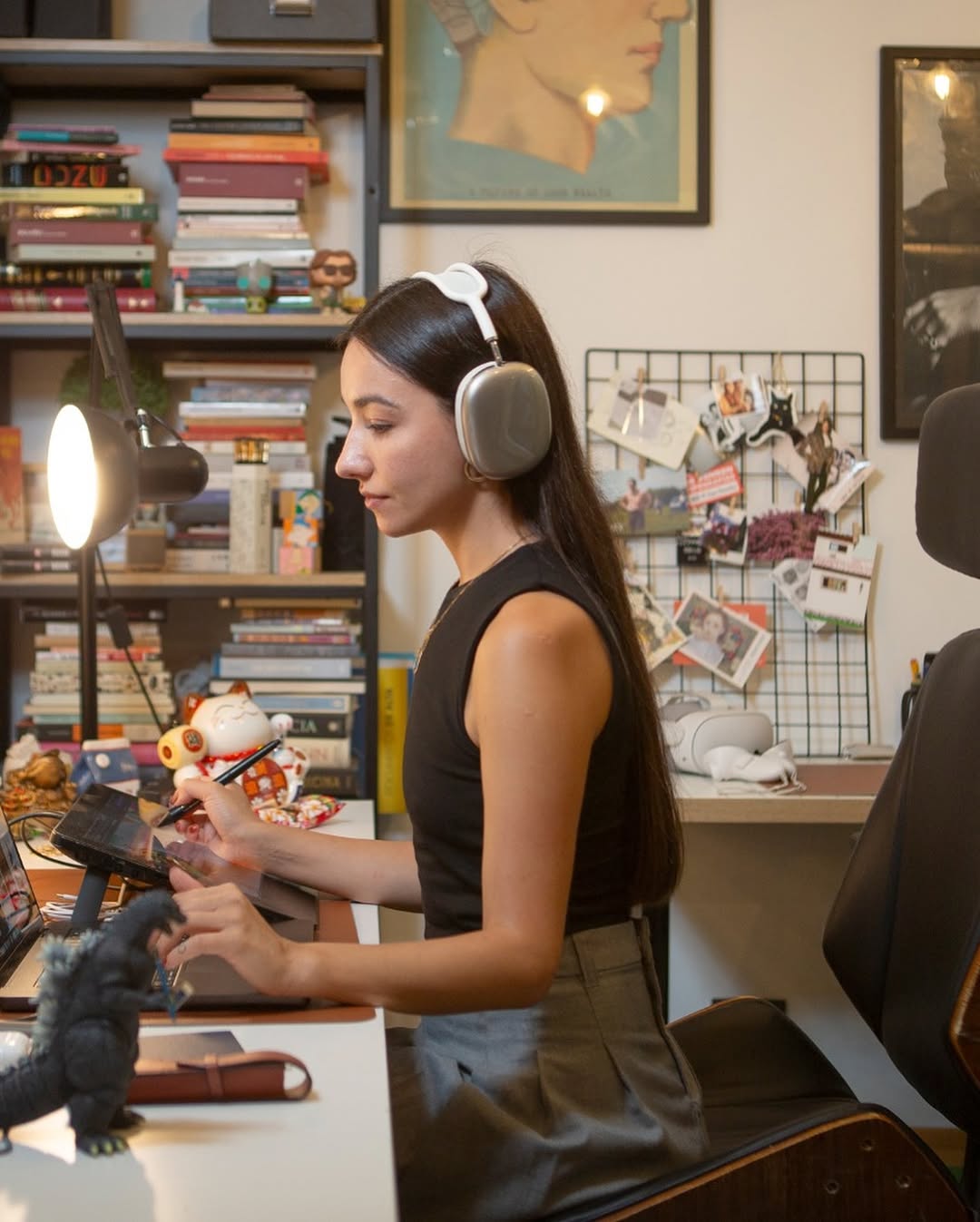 Woman wearing headphones uses a tablet at a desk in an office.