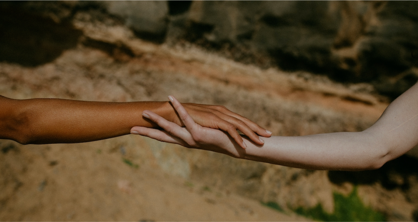 Two hands of different skin colour reaching out and touching