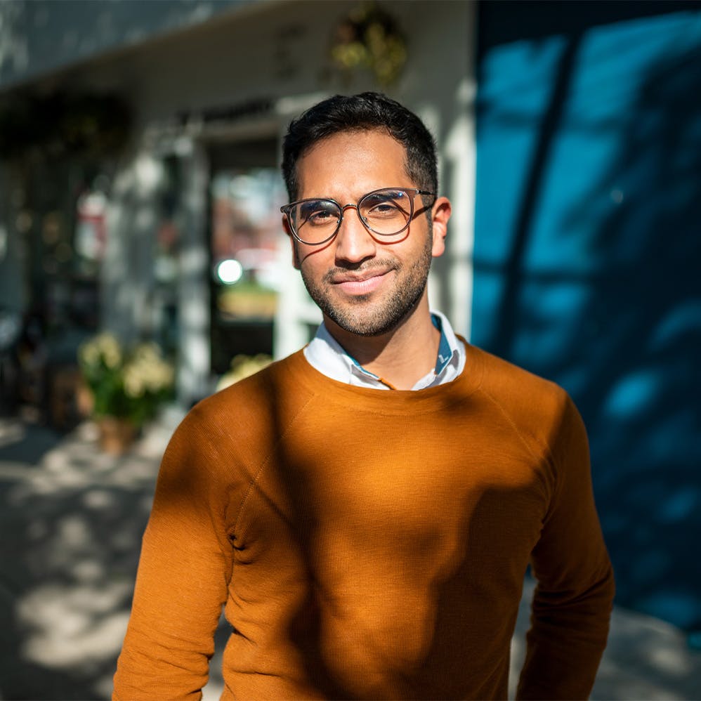 man in glasses standing in front of shops