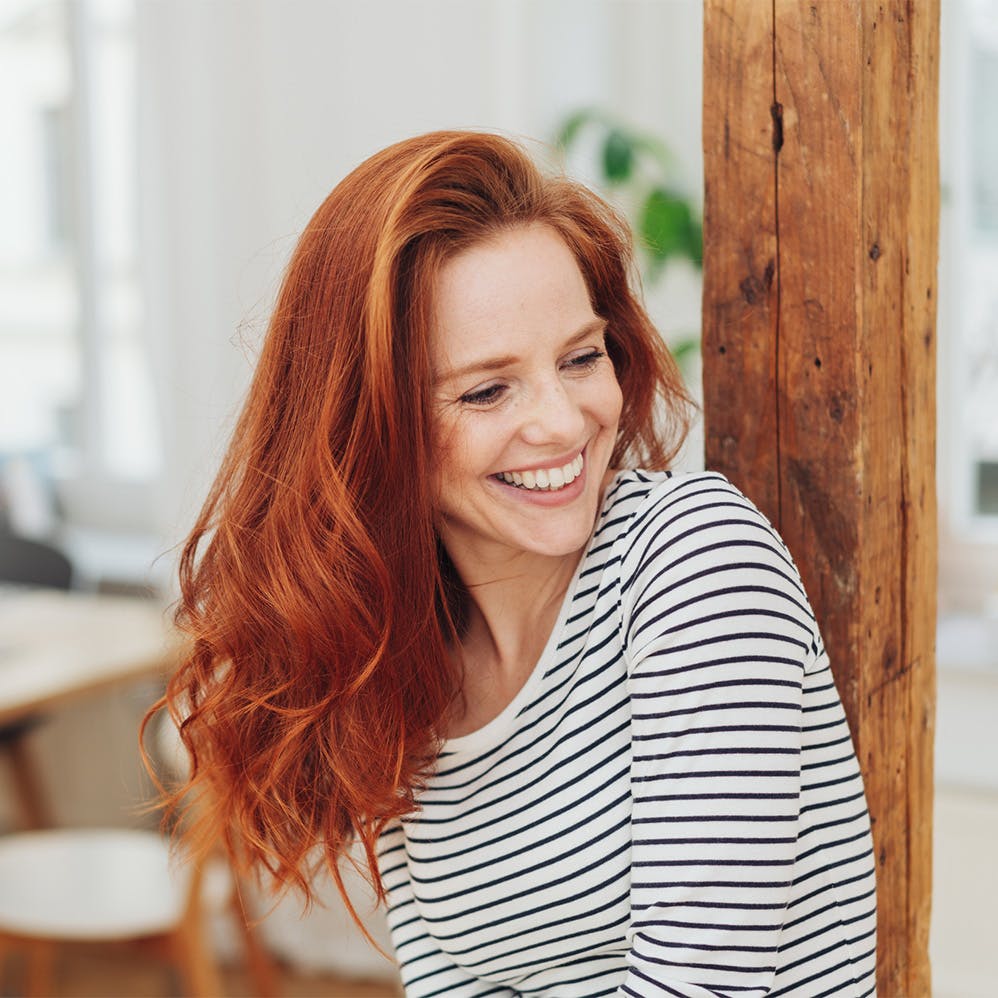 woman smiling while leaning on a post