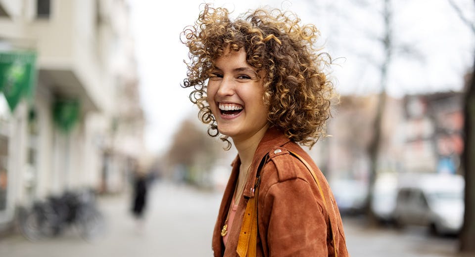 woman laughing on city sidewalk