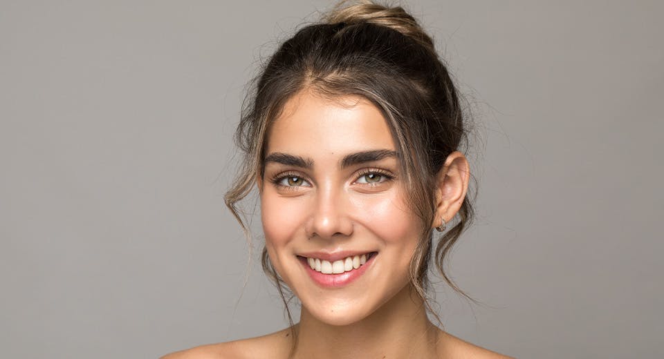 woman smiling in front of grey background