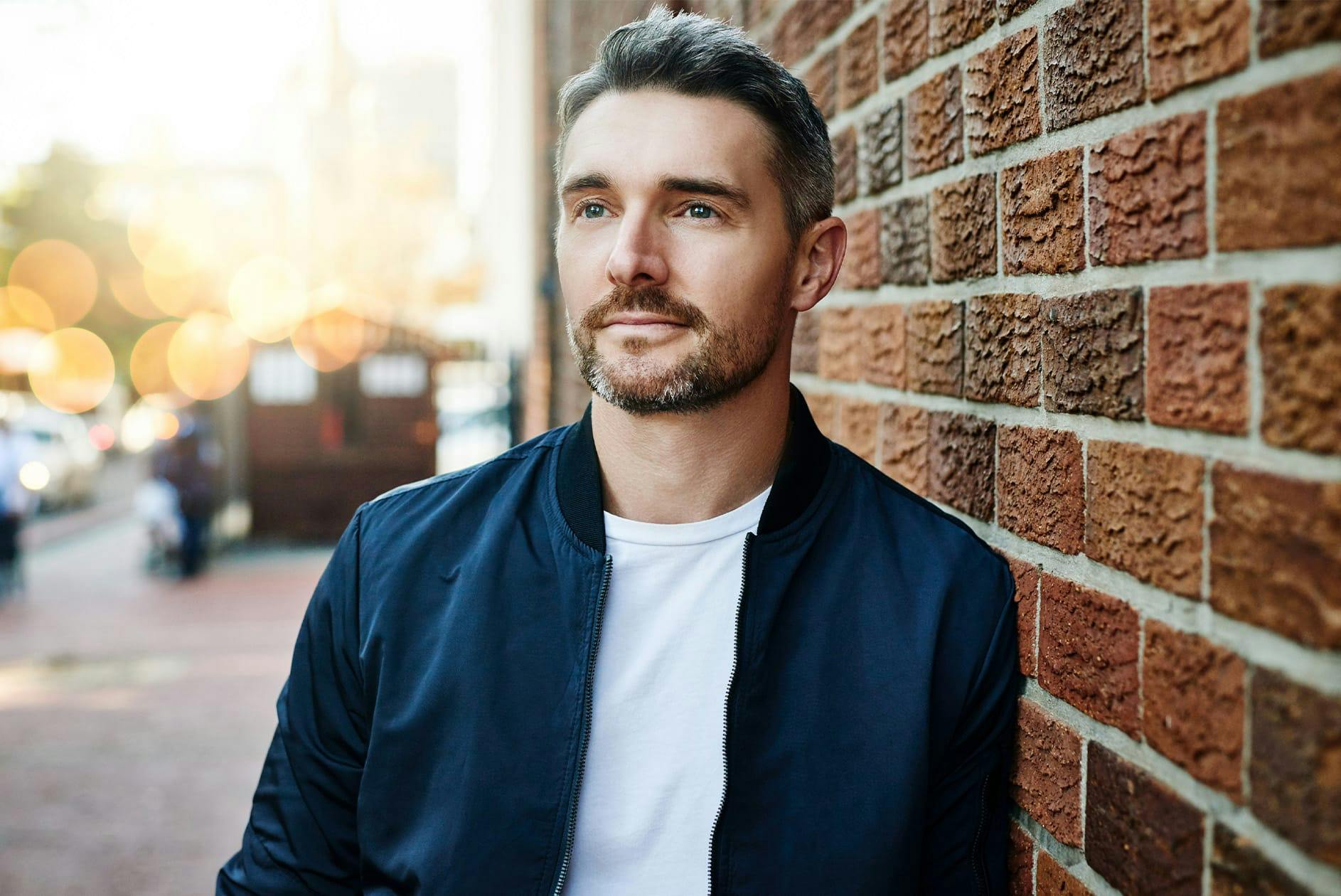 Man leaning against brick wall