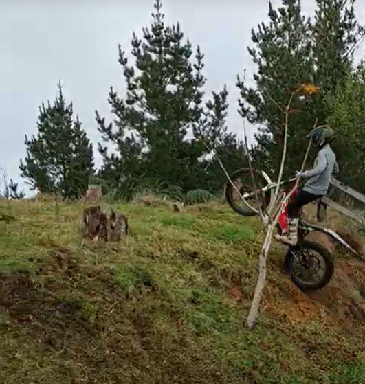 teenage/intermediate rider doing wheelie up hill on trials bike