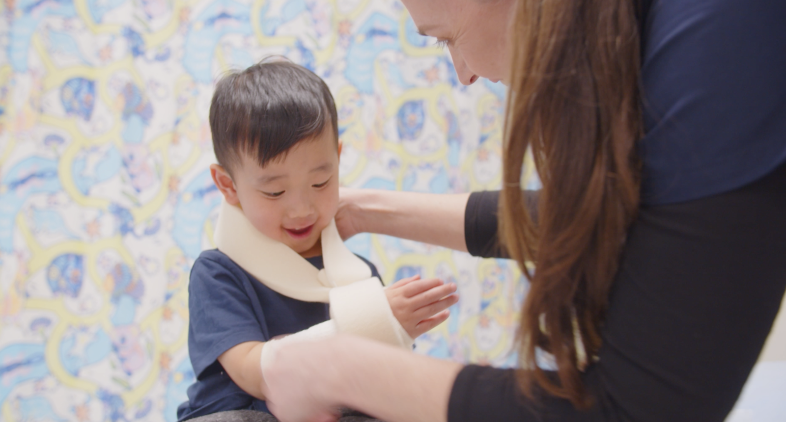 kid patient with nurse applying elbow braces