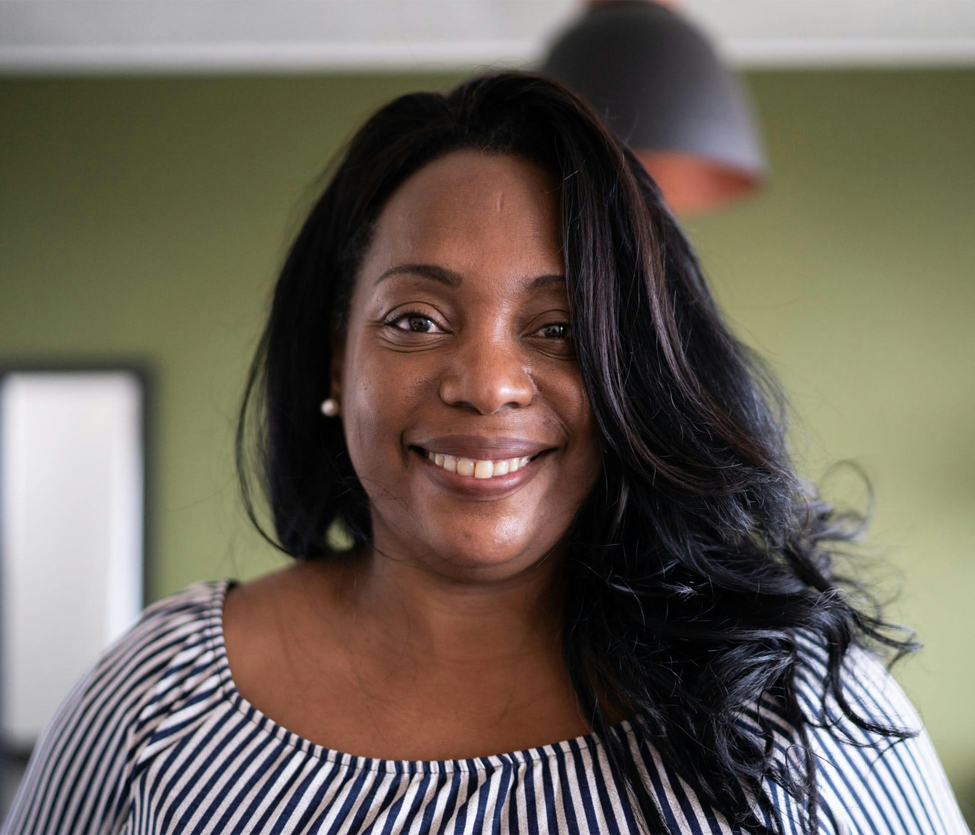 Woman smiling and standing in front of green wall