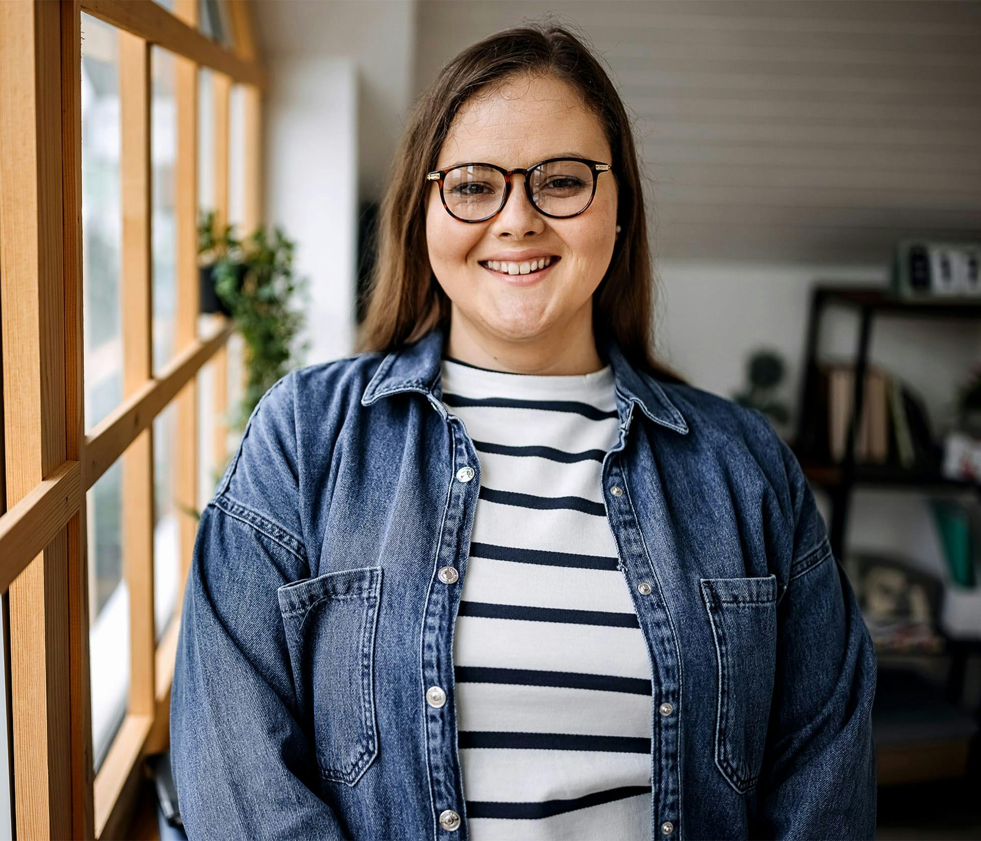 woman smiling and standing next to window