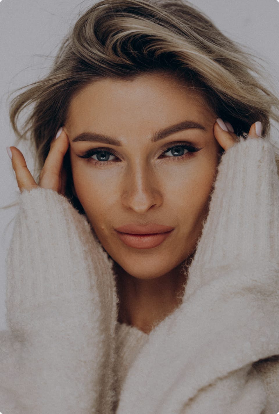 Woman in a sweater with her hands to her face