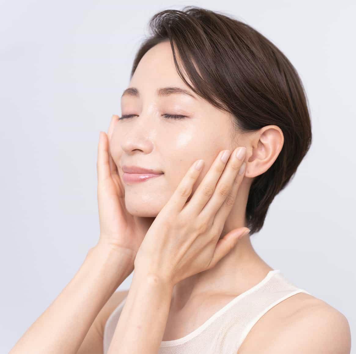 woman with shrot hair closing her eyes and touching her face