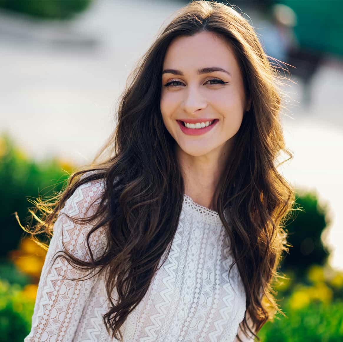 woman with long dark hair wearing a white top