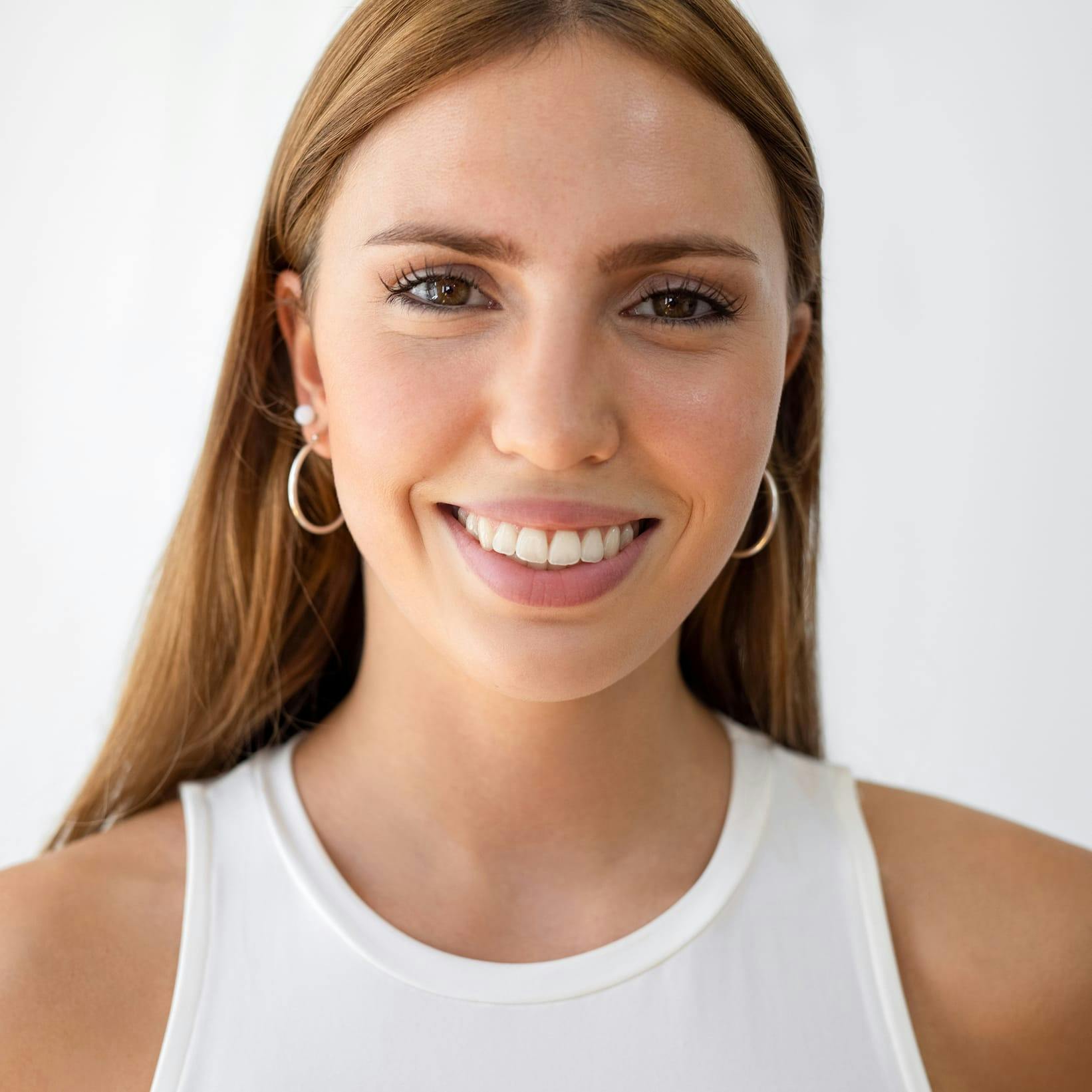 woman in a white top and gold hoop earrings
