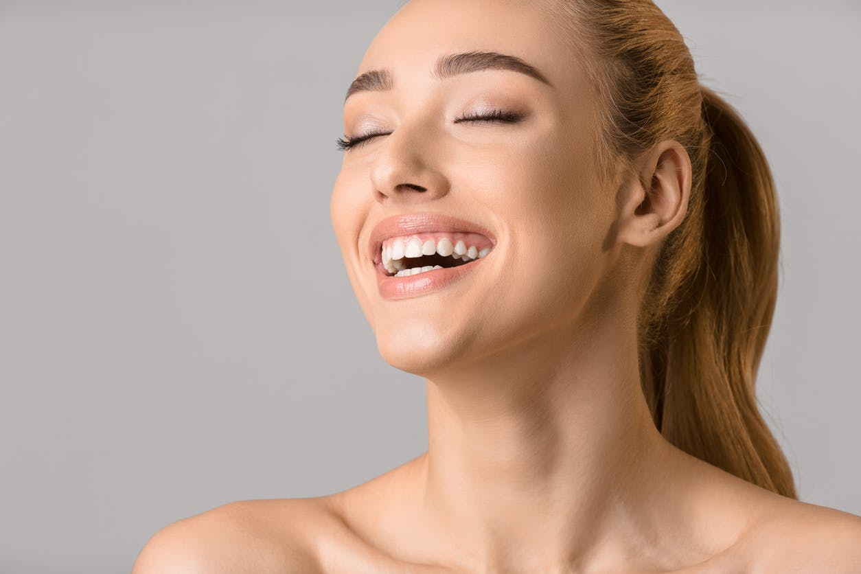 woman laughing wiht her eyes closed in studio shoot. HEr chin is highlighted to show the possible results of a chin augmentaiton in McKinney