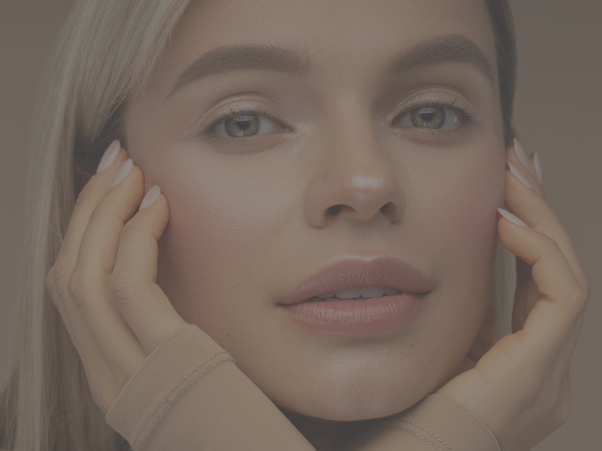 young woman with blonde hair looks at camera in studio shoot. Her glowing skin emulate the potential results of skin resurfacing with laser or chemical peel in McKinney