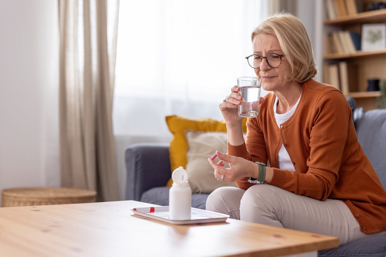 woman in orange cardigan drinking water
