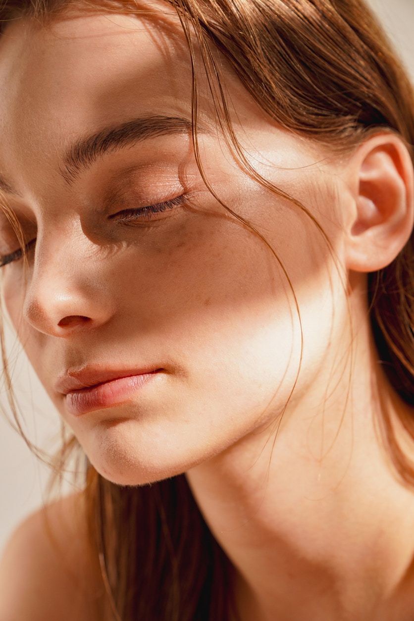 Woman with eyes clsoed an no makeup has the sun glistening on her face. Her face is youthful and wrinkle free to show the possible results of BOTOX in Orlando Fl