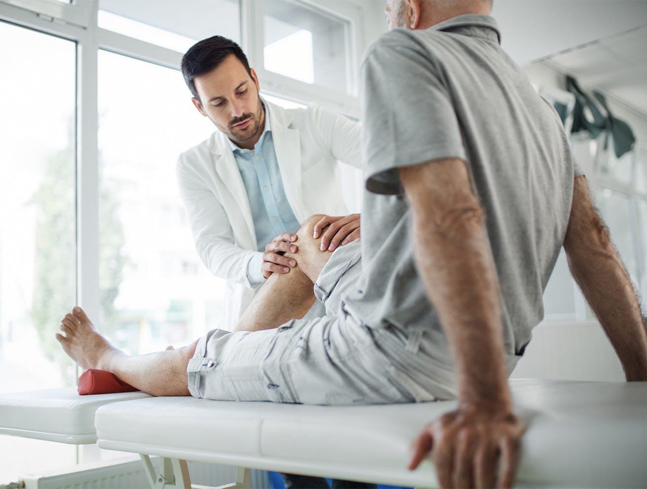 doctor feeling a patient's knee