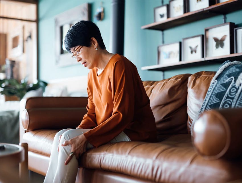 older woman sitting on a couch holding her knee