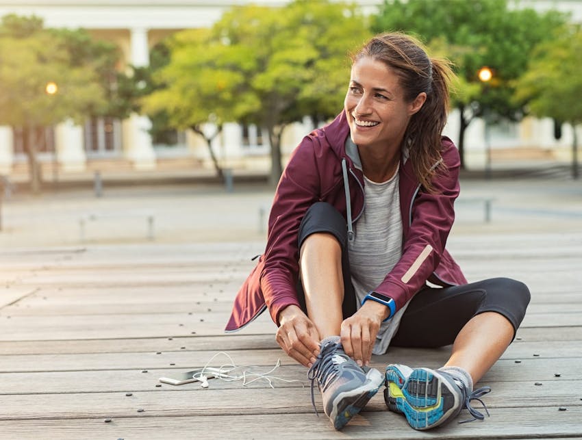 woman sitting on the ground outside fixing her shoes