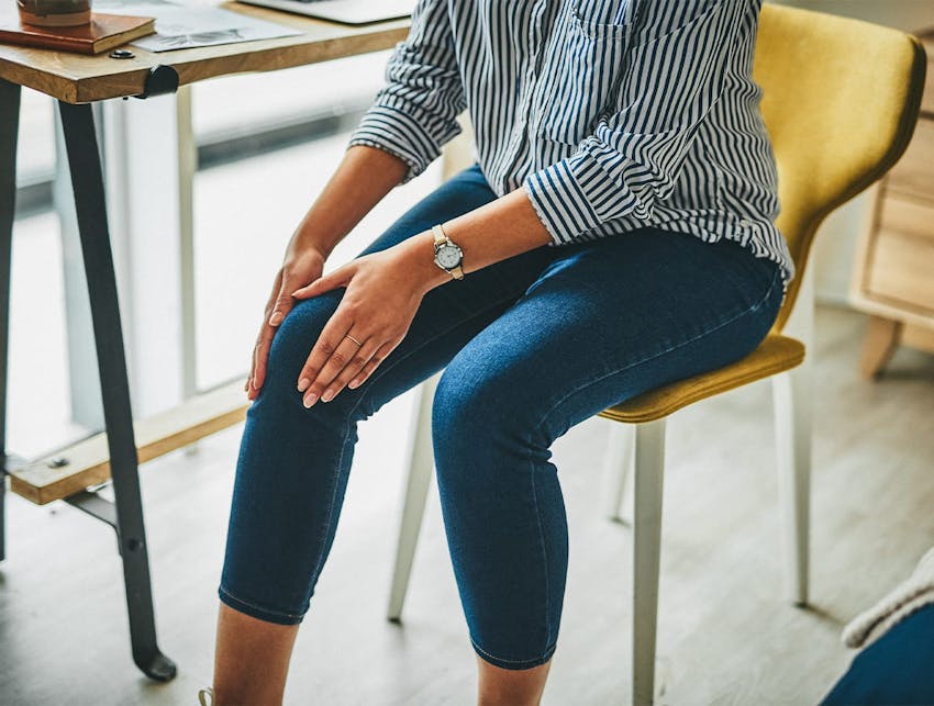 woman sitting on a chair holding her knee